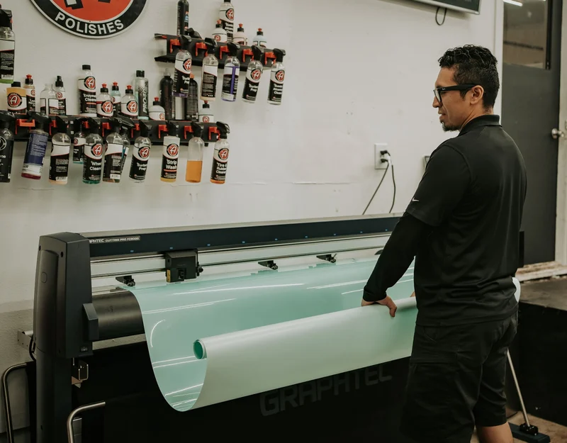 Technician loading protective film into the Graphtec precision cutter