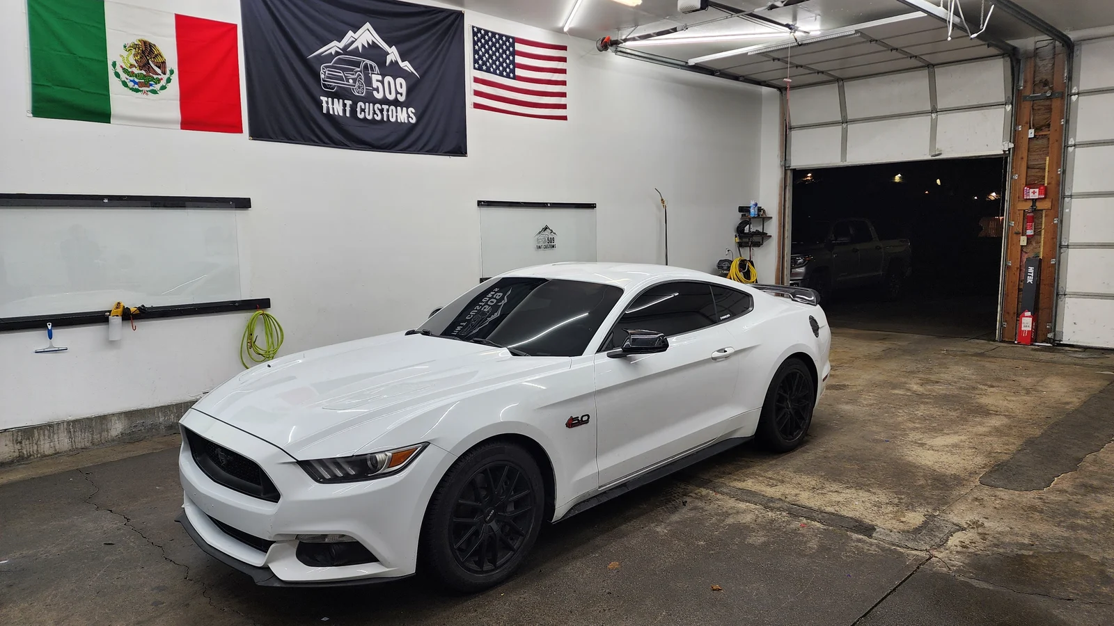 White Ford Mustang with tinted windows inside the 509 Tint Customs shop